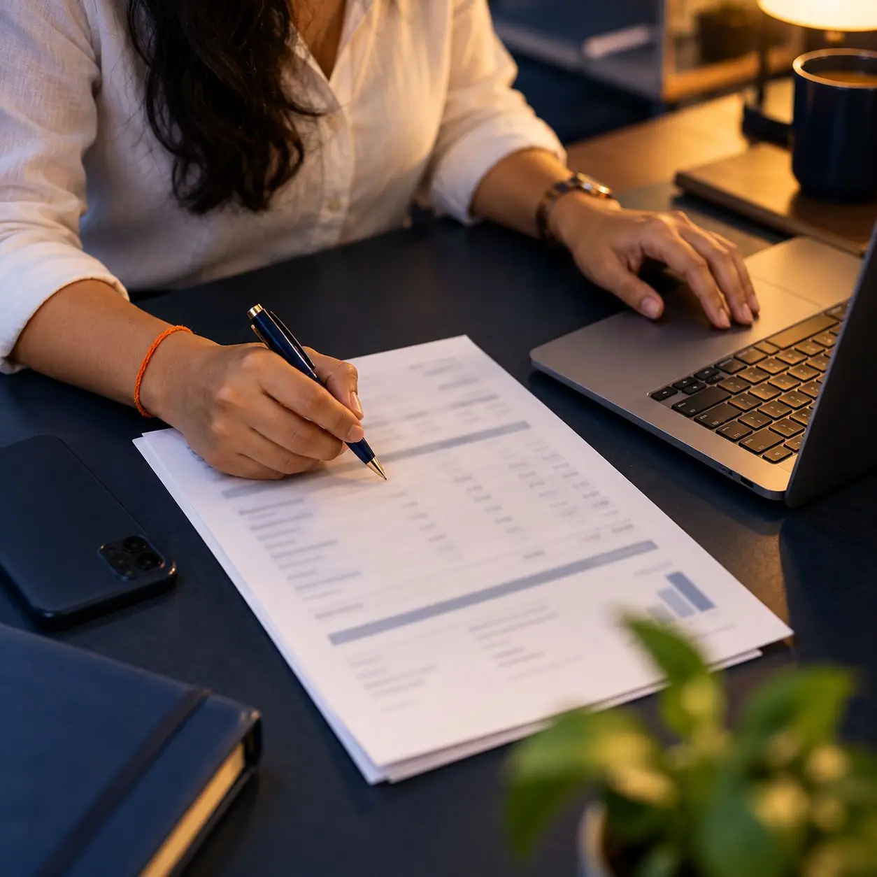 Hands checking a printed invoice beside a laptop